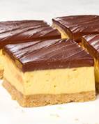 Layered dessert squares with a crumbly base, creamy yellow filling, and a glossy chocolate topping.